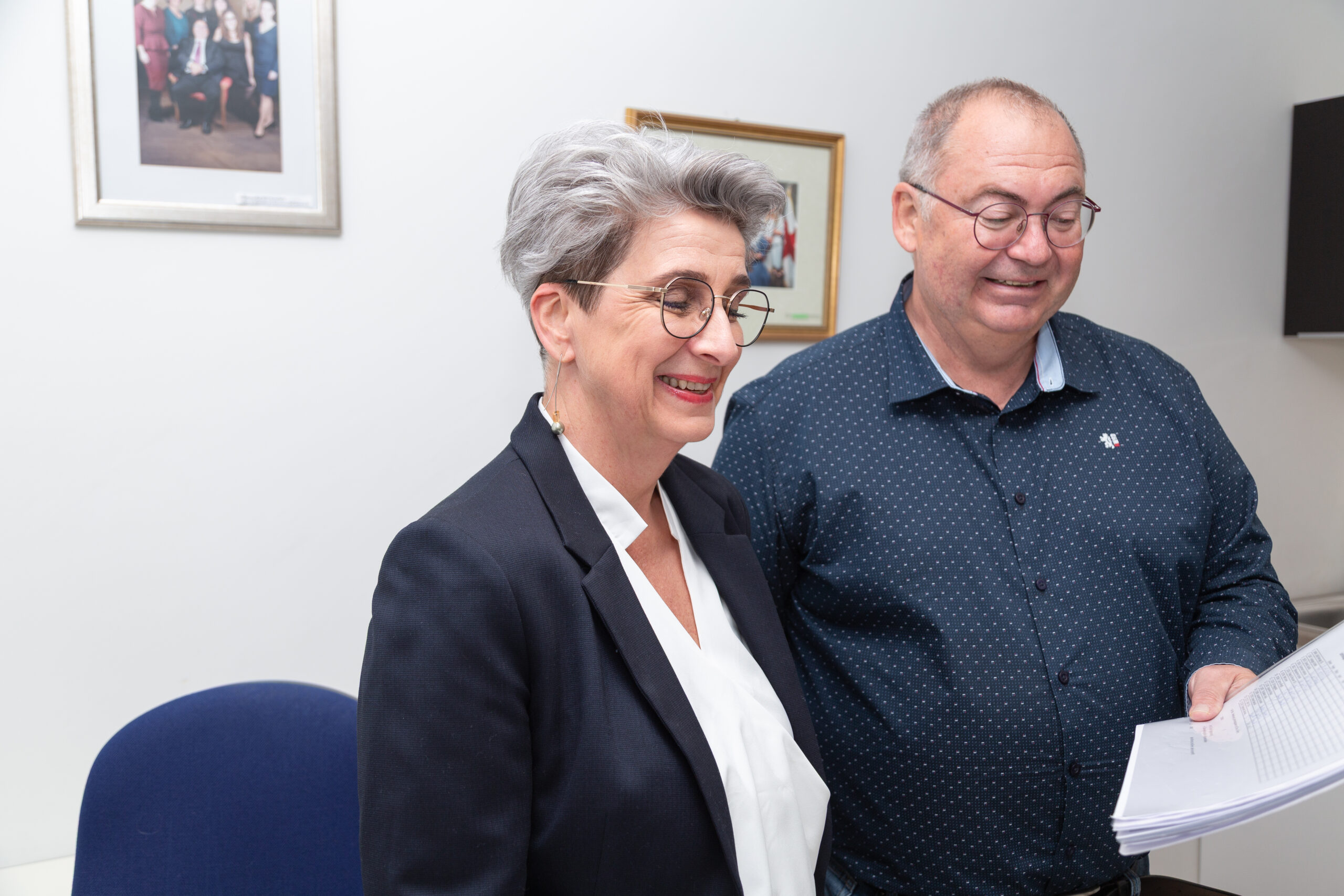Ihre vertrauenswürdige Steuerberatungskanzlei in der Steiermark - Sekretärin (links) lächelnd in einer Interaktion mit Steuerberater (rechts). Beide schauen auf ein Dokument und unterhalten sich.