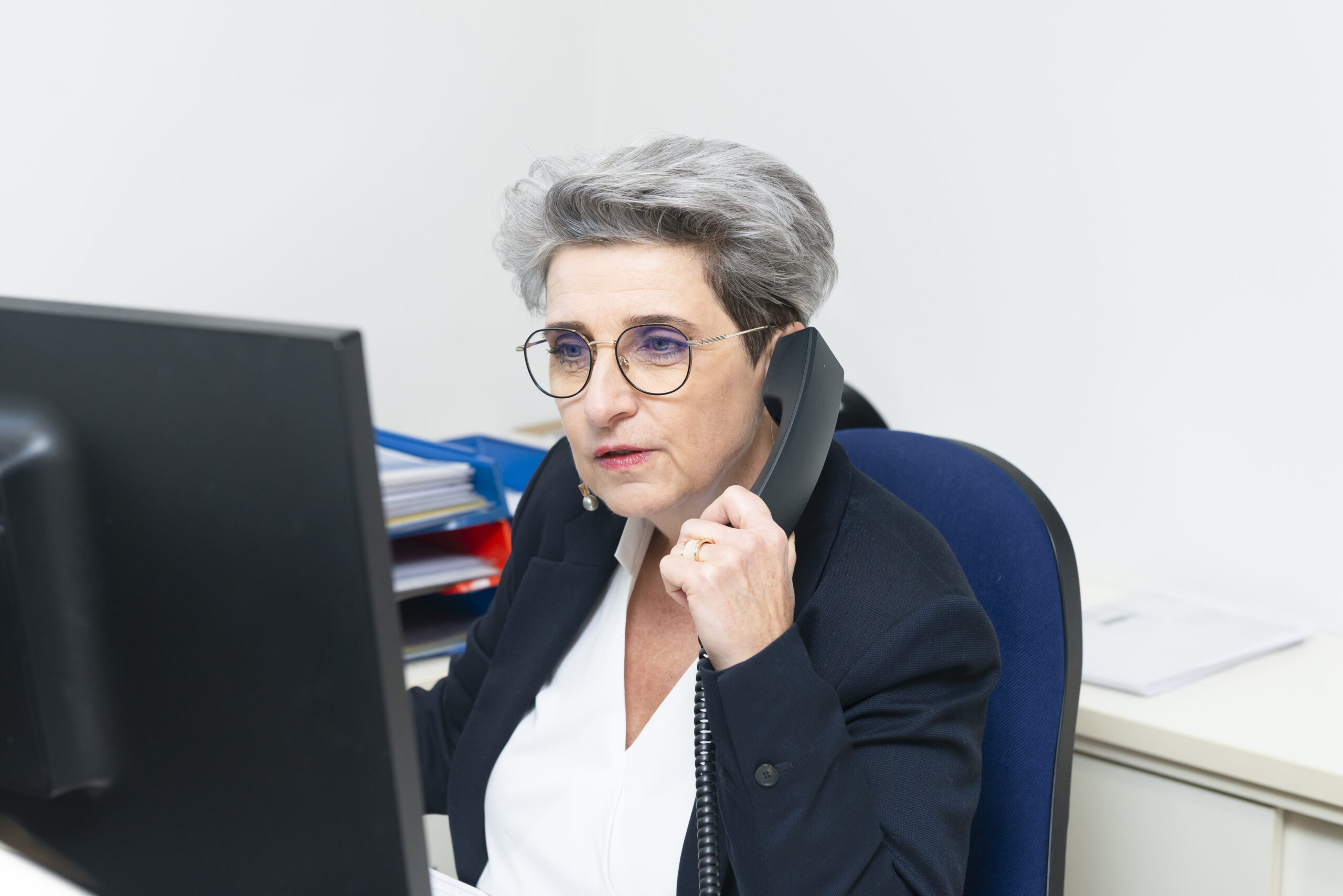 Auf diesem Bild sieht man Eveline Podrepsek, Sekreätrin aus Graz und Graz & Umgebung. Sie schaut ernst und konzentriert auf ihren Computer und telefoniert währenddessen.